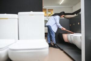 Young woman choosing bathroom toilet bowl and utensils for his home.