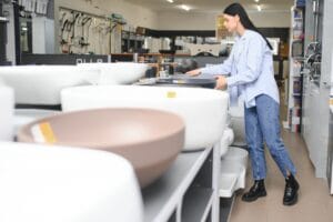Woman choosing bathroom sink in store.